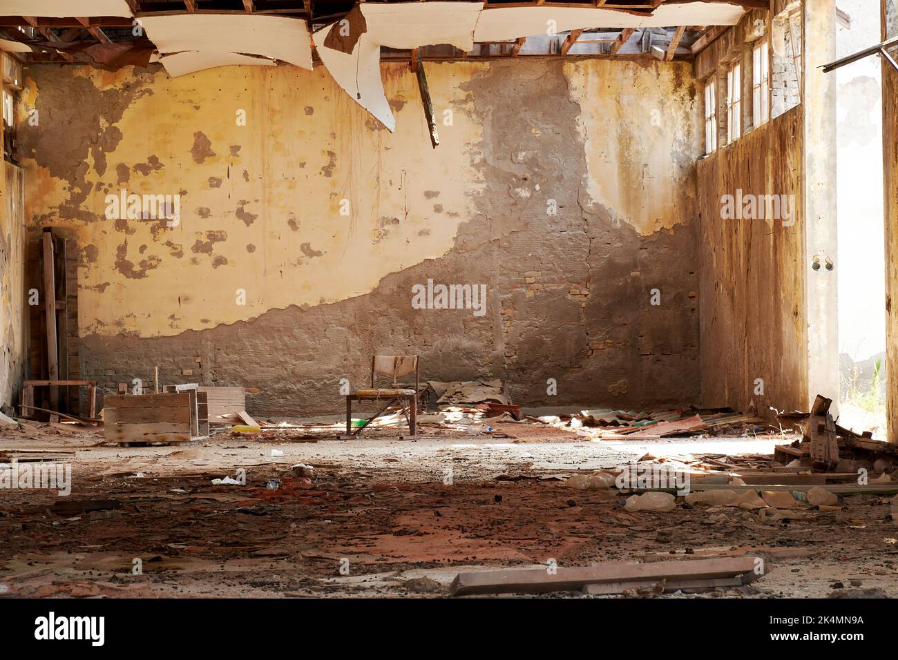 Warravaged apartment with a lone chair in the center of the room. Sad