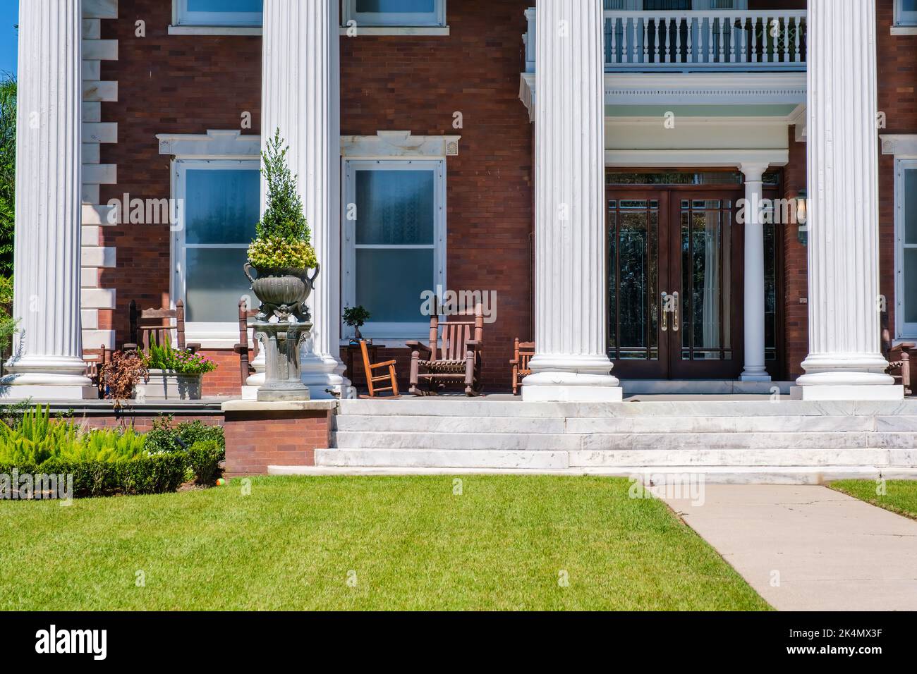 NEW ORLEANS, LA, USA - SEPTEMBER 27, 2022: Portion of front porch of mansion on St. Charles Avenue showing lawn, architectural features, and furniture Stock Photo