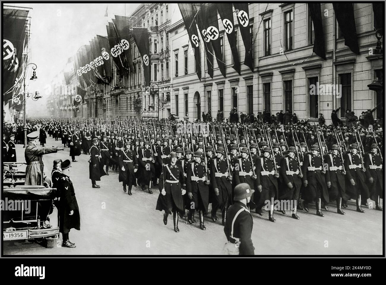Leibstandarte Waffen SS  Adolf Hitler in his open top Mercedes Motorcar salutes a parade of his personal bodyguard regiment, the 1st SS Division Leibstandarte Waffen SS with buildings bedecked with swastika flags January 30th,1937 Stock Photo
