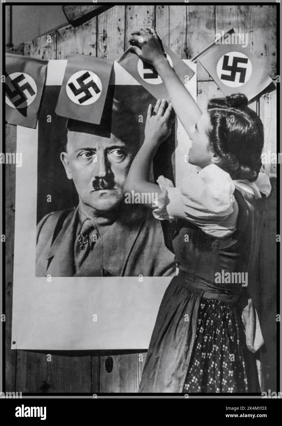 Nazi German Troops occupation with girl in Czechoslovakia dress pinning celebratory swastika flags around portrait of Adolf Hitler in military uniform to show support for Nazi Germany 1938 Sudetenland Czechoslovakia Stock Photo
