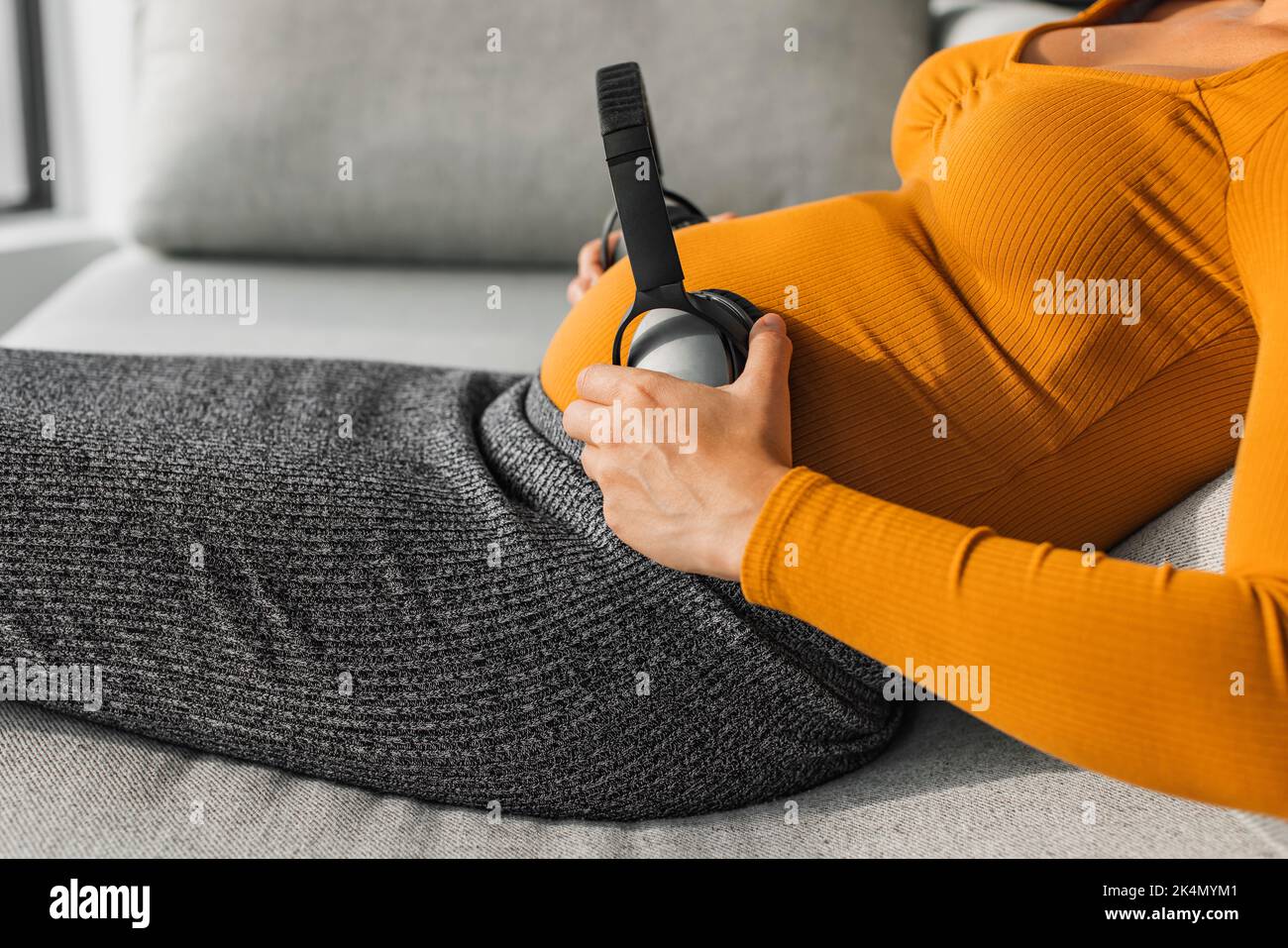 Pregnant woman holding headphones for baby in womb to listen to music