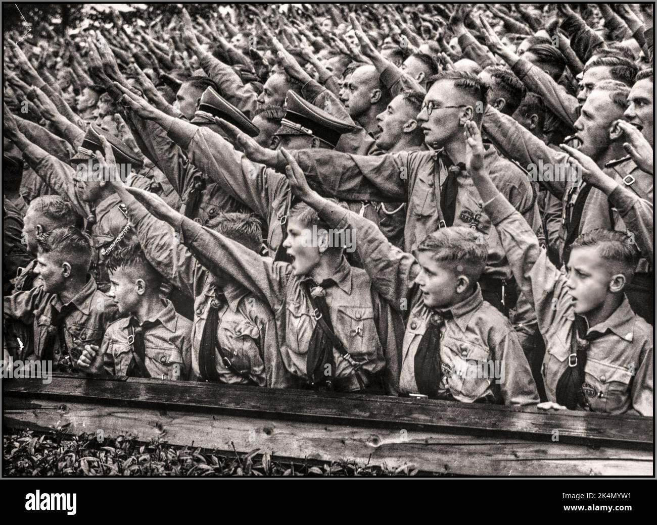 HEIL HITLER Hitler Youth Hitlerjugend salutes. Nazi indoctrination with boys and youths passionately giving Heil Hitler salutes at a Nazi Nuremberg Rally Nazi Germany 1937 Stock Photo
