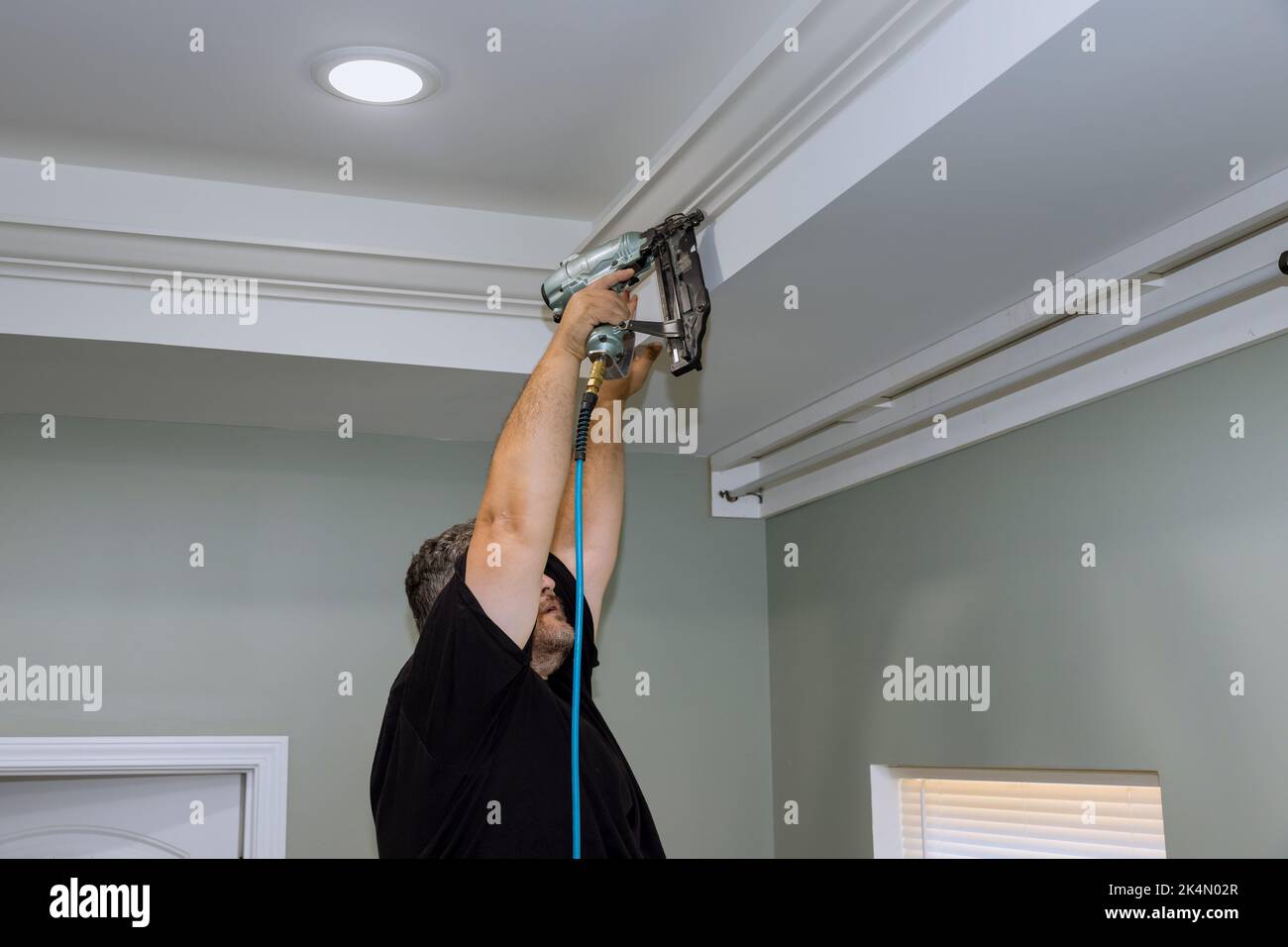 The a professional carpenter nailing wooden crown molding between the