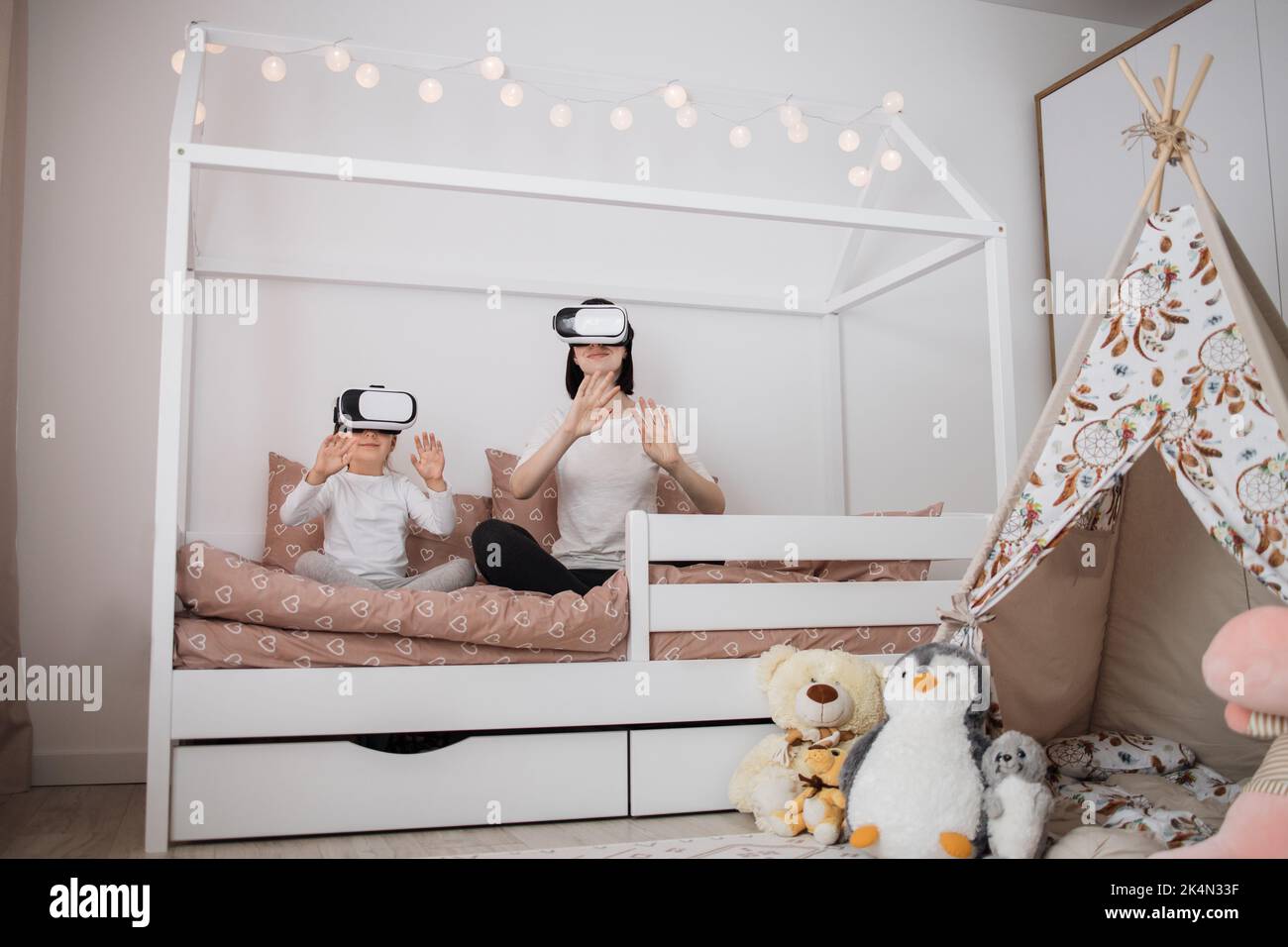 Attractive smiling caucasian woman with her cute little daughter, using virtual reality devices