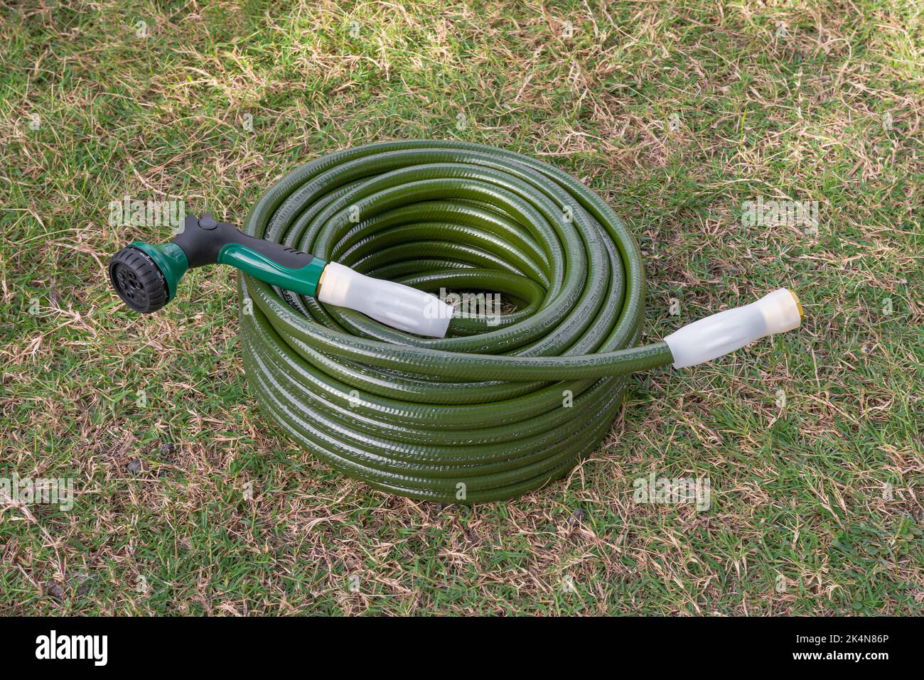 Garden hose green lawn new gardening equipment wrapped up coiled Stock Photo