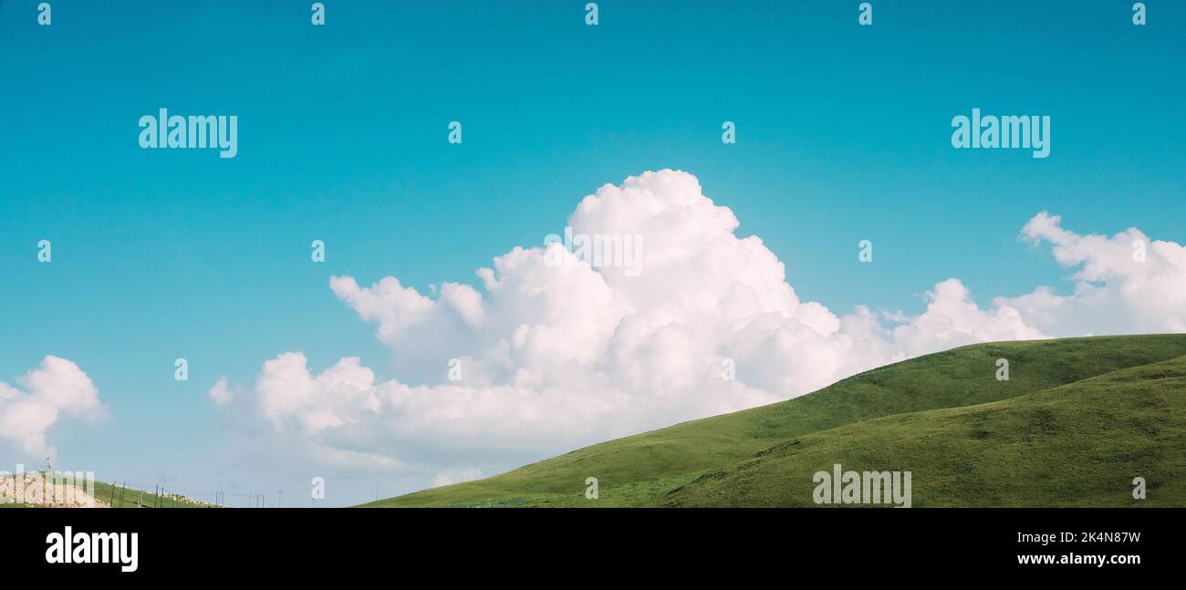 A low angle shot of a fluffy white cloud over a green hill Stock Photo ...