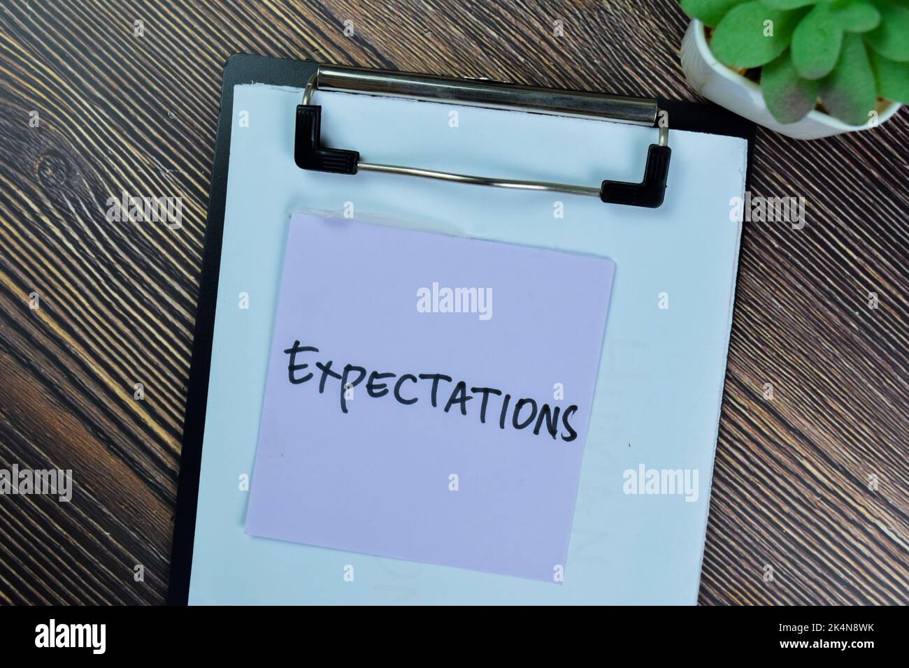 Concept of Expectations write on sticky notes isolated on Wooden Table. Stock Photo