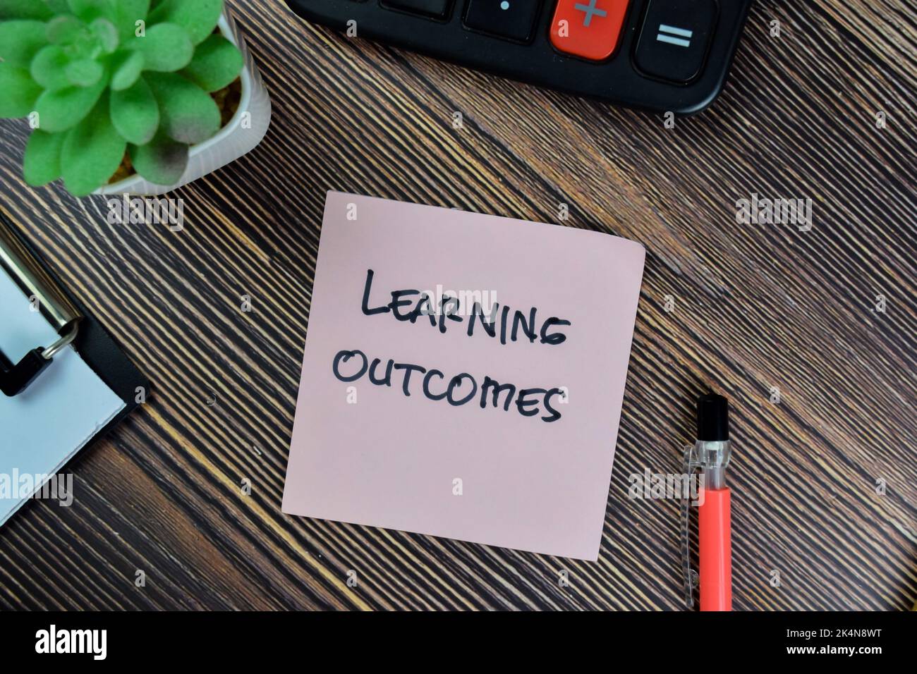 Concept of Learning Outcomes write on sticky notes isolated on Wooden Table. Stock Photo