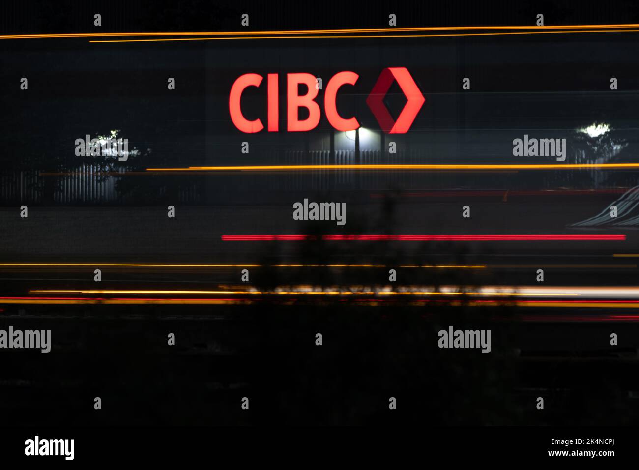 The CIBC logo illuminated on a sign, seen at night along a busy highway; CIBC, Canadian Imperial Bank of Commerce is the 5th largest bank in Canada. Stock Photo