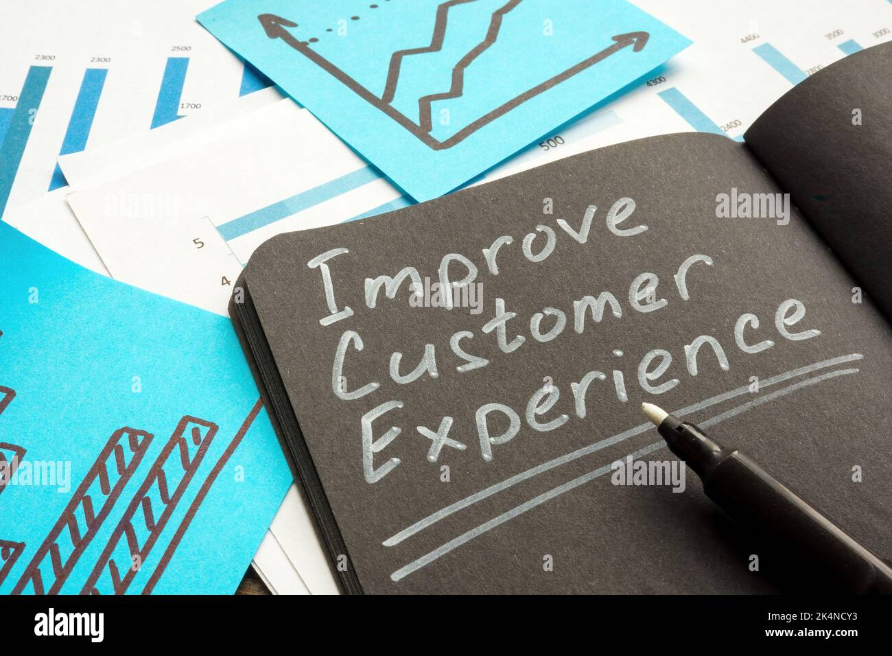 Handwritten inscription Improve customer experience in the notebook. Stock Photo