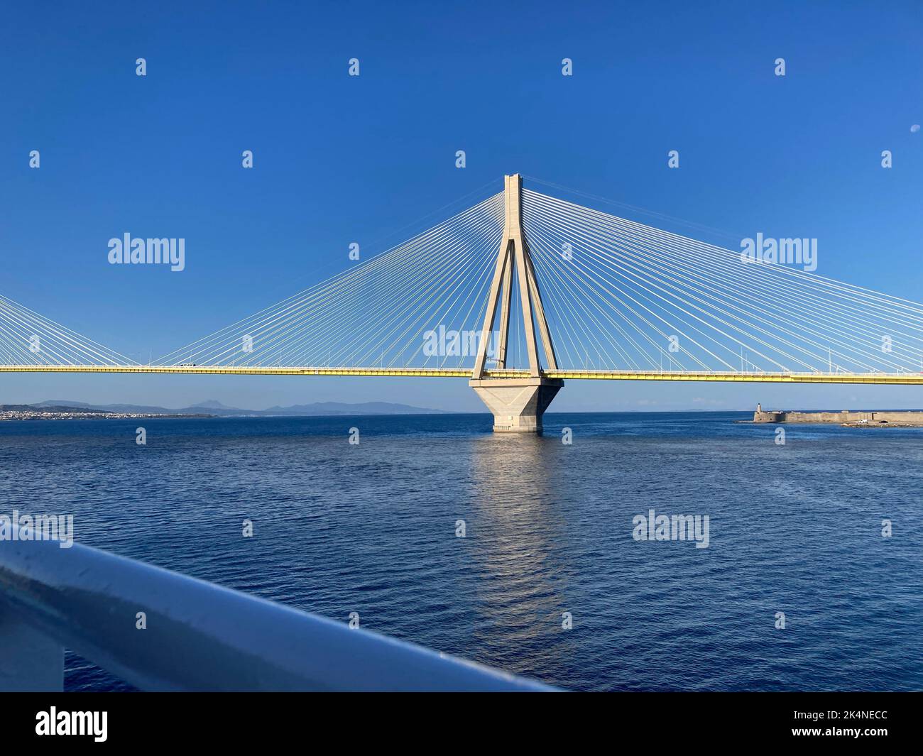 A landscape view of the Rion-Antirion Bridge on blue sea with blue sky