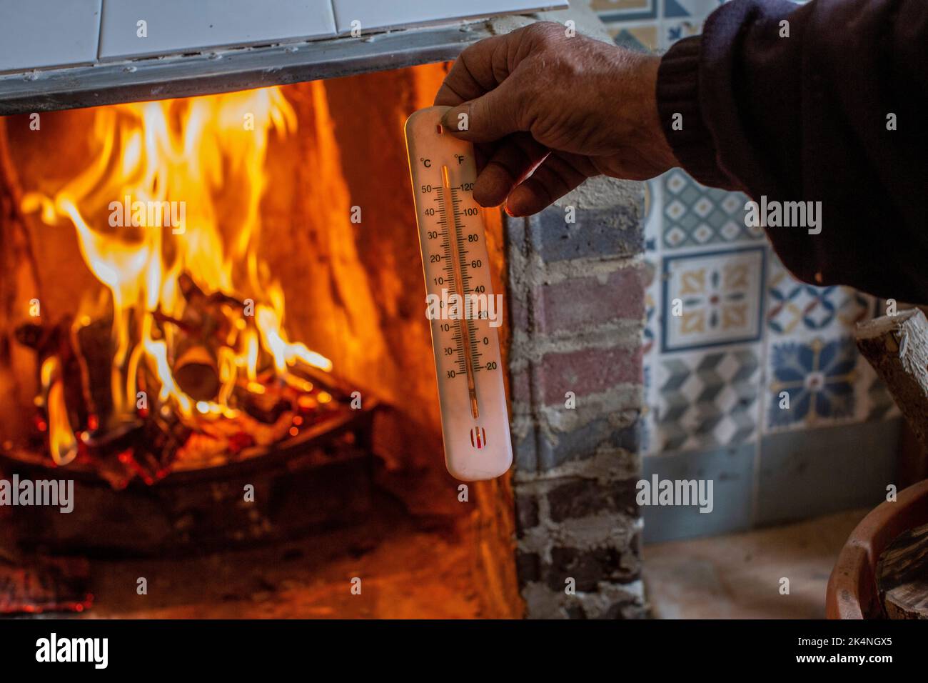 London, UK. Sept 29 2022 .Close up of hand holding a thermometer measuring temperature of fireplace . Stock Photo
