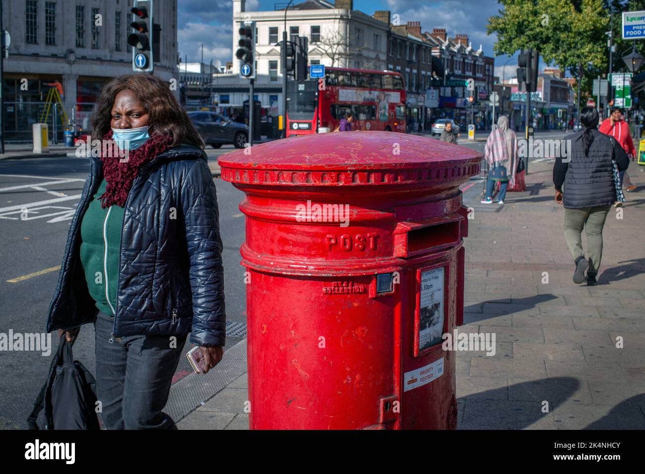 London, UK. Sept 29 2022 . Workers Union take further national strike action. Woman walks by Traditional red post box in Lewisham,London ,England . Stock Photo