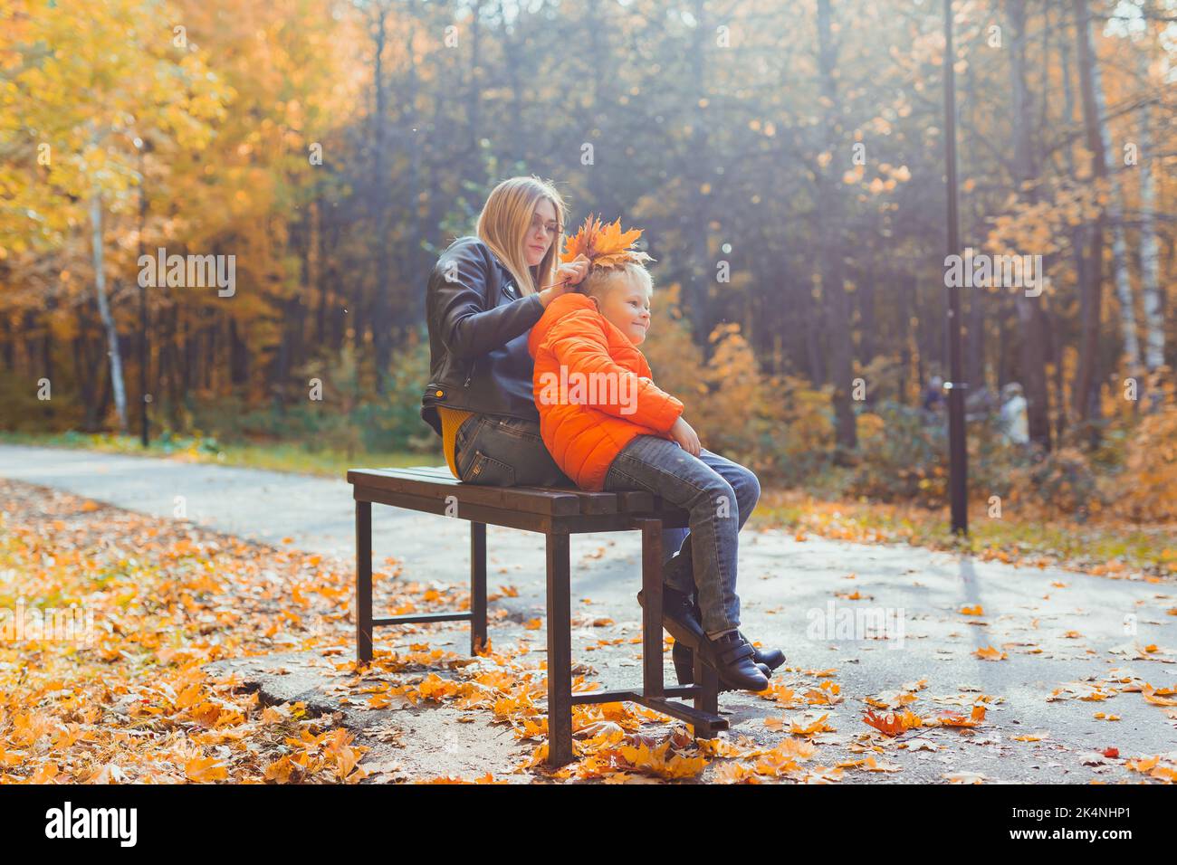 Single parent mother and child boy in the autumn in park sit on bench ...
