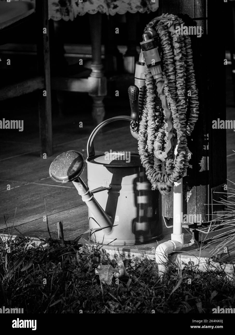 The Watering Can and Hose Sit Idle Stock Photo