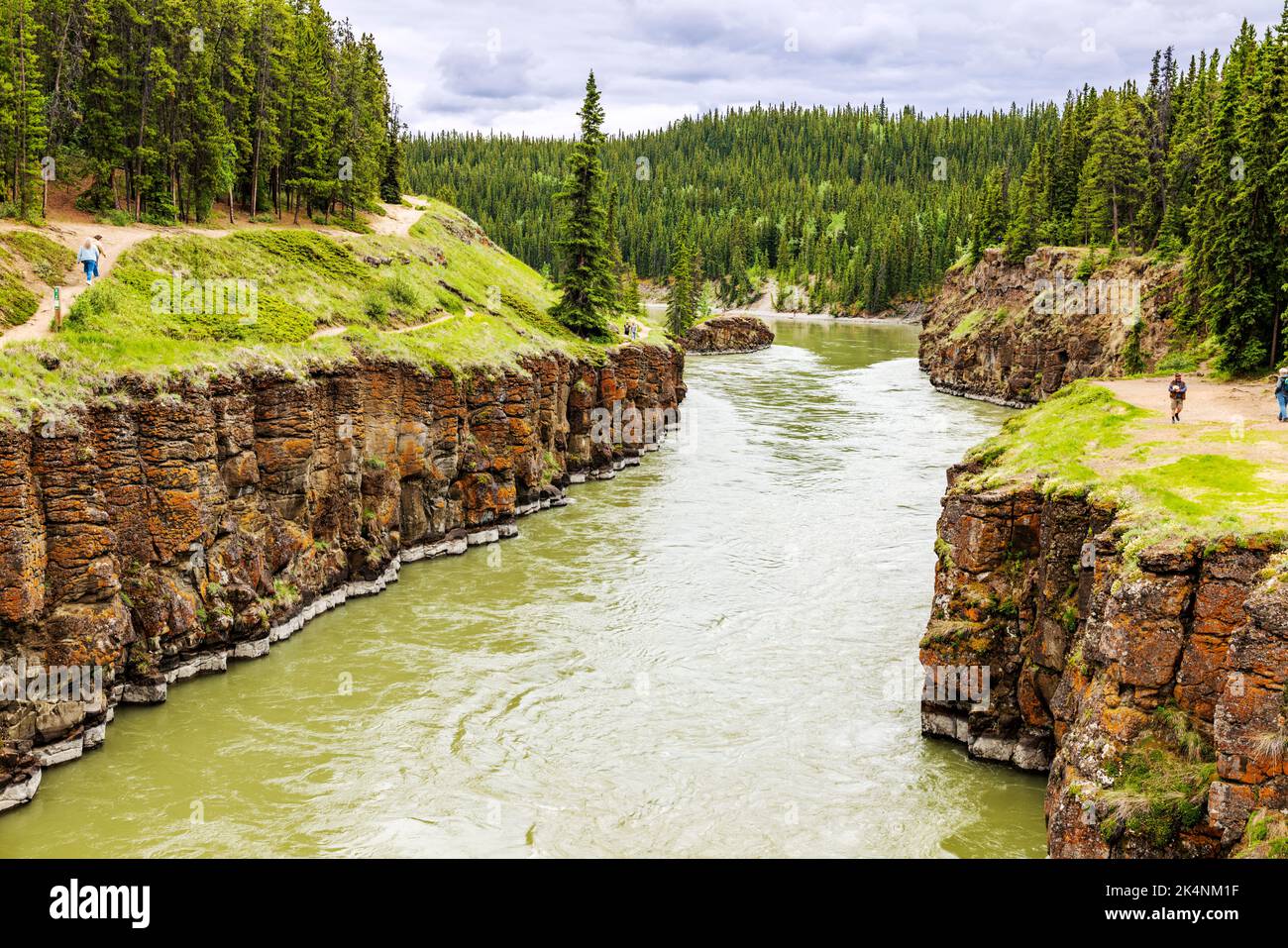 Tourists explore basalt rock formations; Miles Canyon; Whitehorse