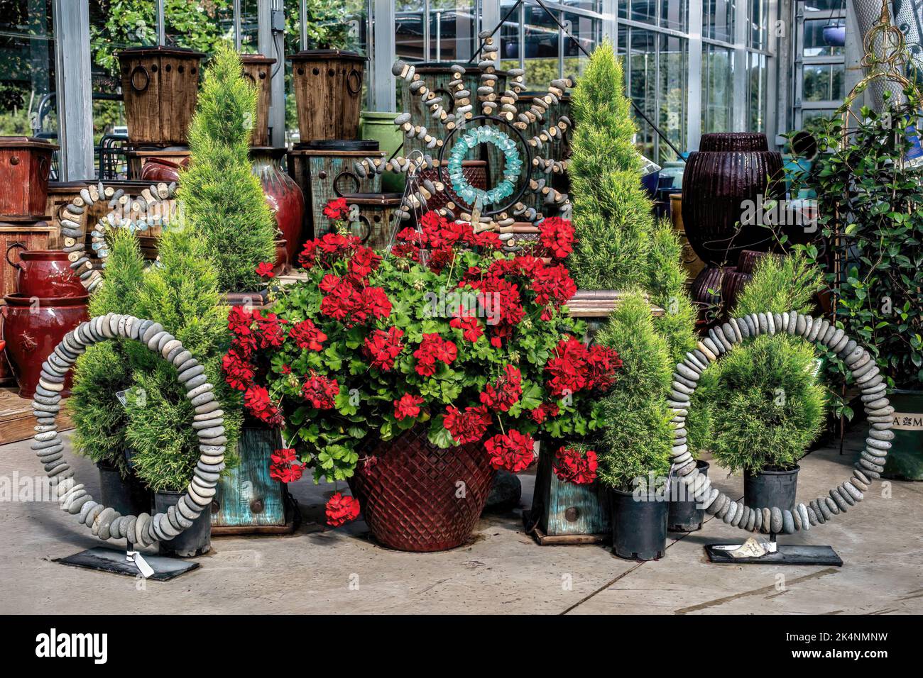 Big pot full of pretty red geraniums and a unique display of stone art