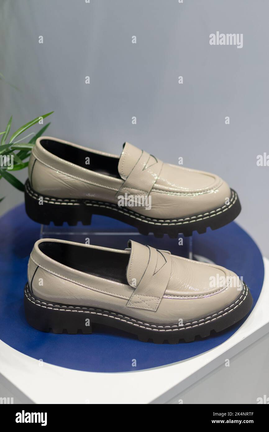 White shiny beautiful fashionable female loafers shoes with dark sole. Studio shoot on white background for magazine, website in Internet or catalog. Stock Photo