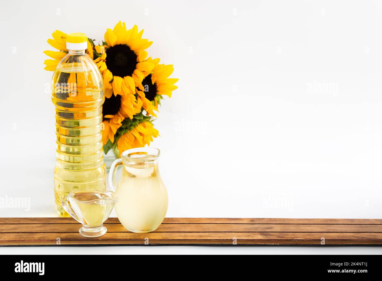 Plastic bottle and glass jars with sunflower oil and bouquet on wood Stock Photo