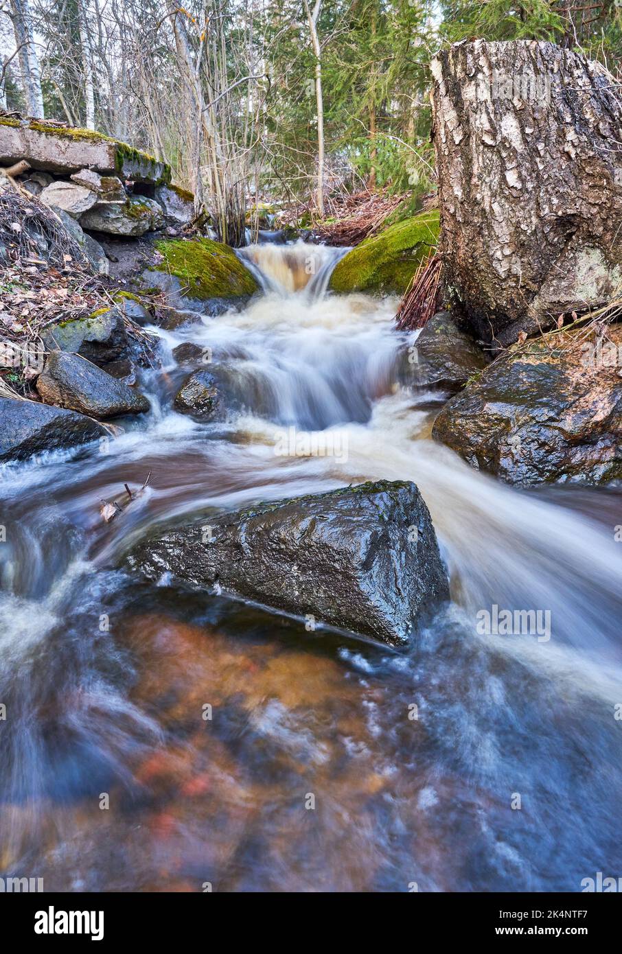 A long exposure shot of a waterfall flowing over mossy rocks in a ...