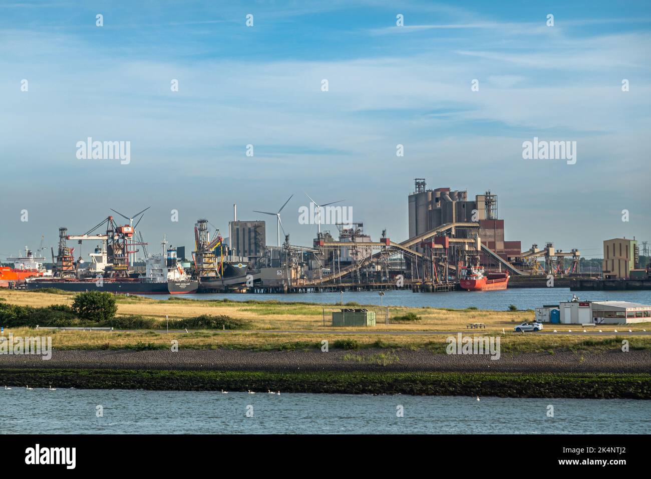 Rotterdam, Netherlands - July 11, 2022: Europoort Bulk Sevices terminal and silos in Beneluxhaven with ships being handled under blue evening sky. Stock Photo