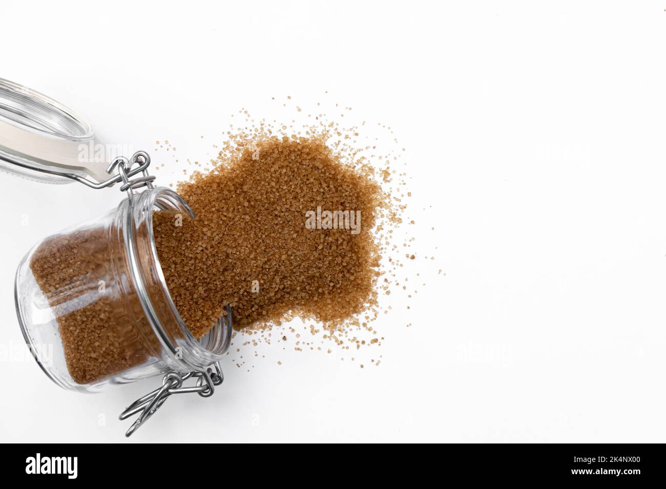 cane sugar in glass jar isolated on white background, natural product used in cooking and cosmetics, macro photo of seasoning, close up, heap of unref Stock Photo