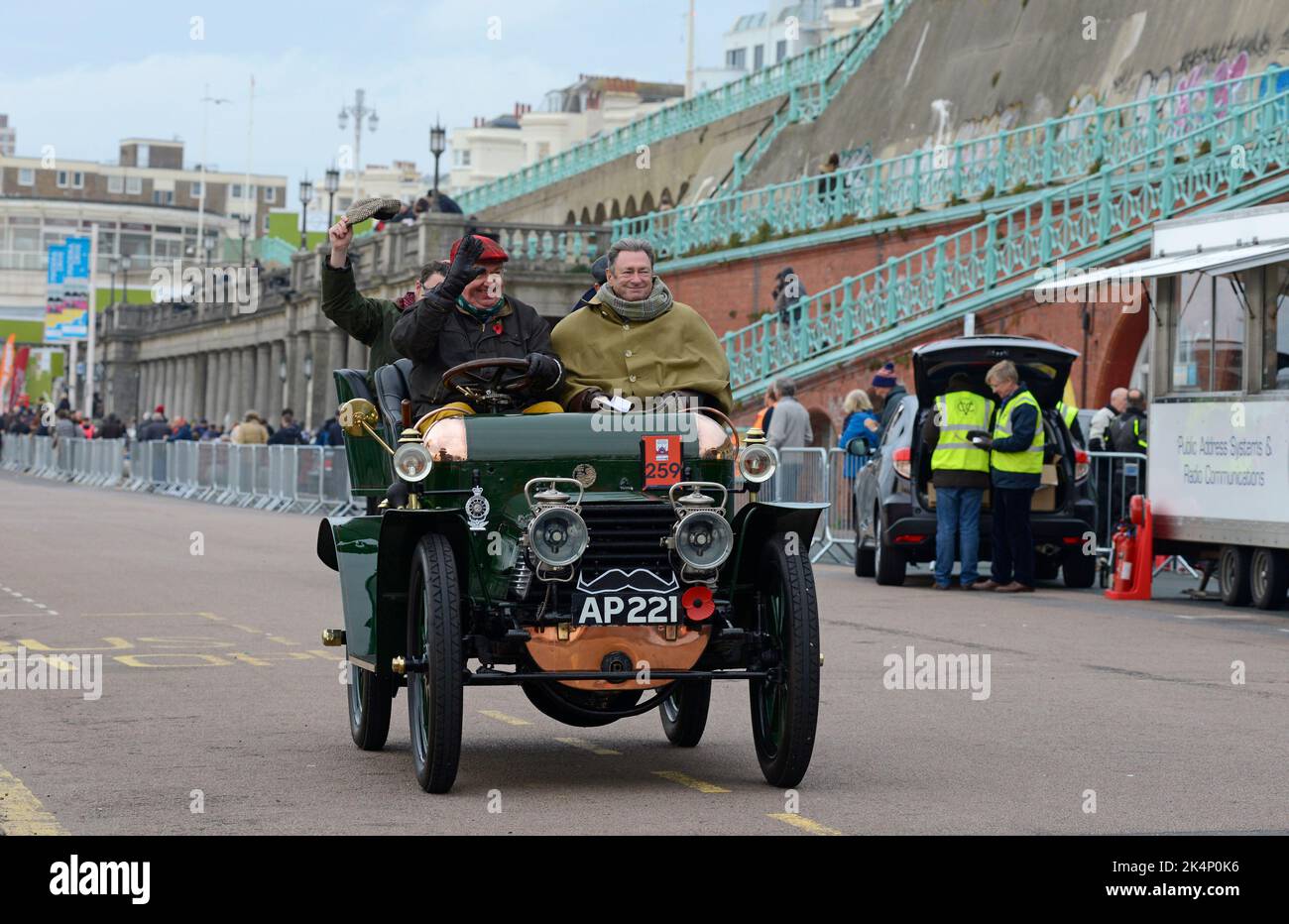 The driver of a 1903 Daimler, with celebrity Alan Titchmarsh as a passenger, waves as he heads for the parking area after the London to Brighton run. Stock Photo