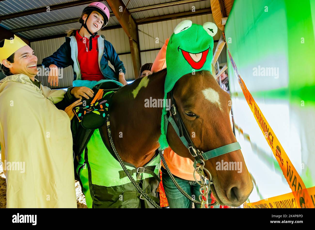 A girl sits astride a therapy horse at a Halloween costume party for