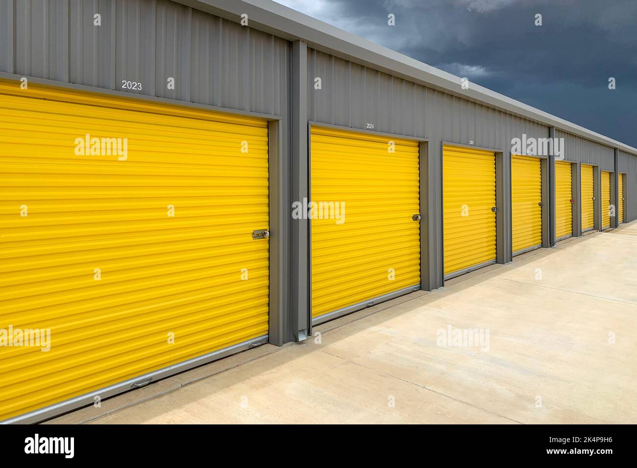 Exterior of a commercial warehouse with yellow roller doors, garages