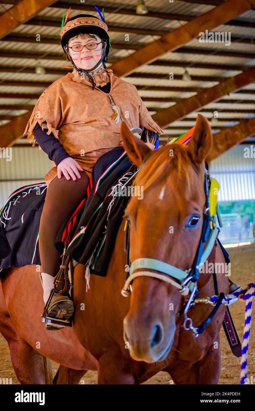 A child rides a therapy horse at a Halloween costume party for riders
