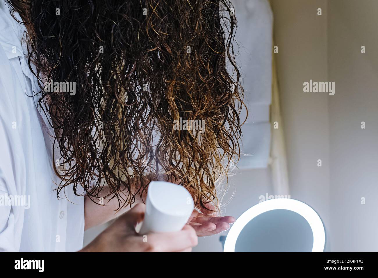 Woman spraying her hair with water to to form curls. Applying curly