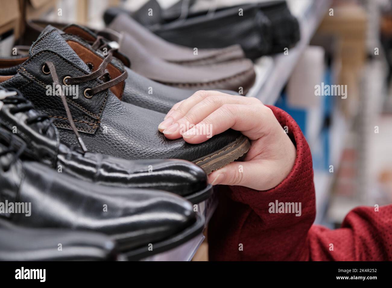 Woman in a clothing store chooses patent leather shoes under a business