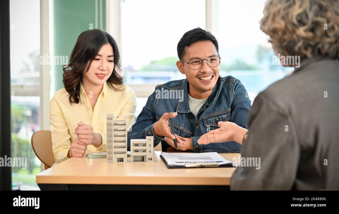 Lovely Asian couple meets with their real estate agent or apartment broker to discuss and summarize the householder's insurance and down payment. Real Stock Photo