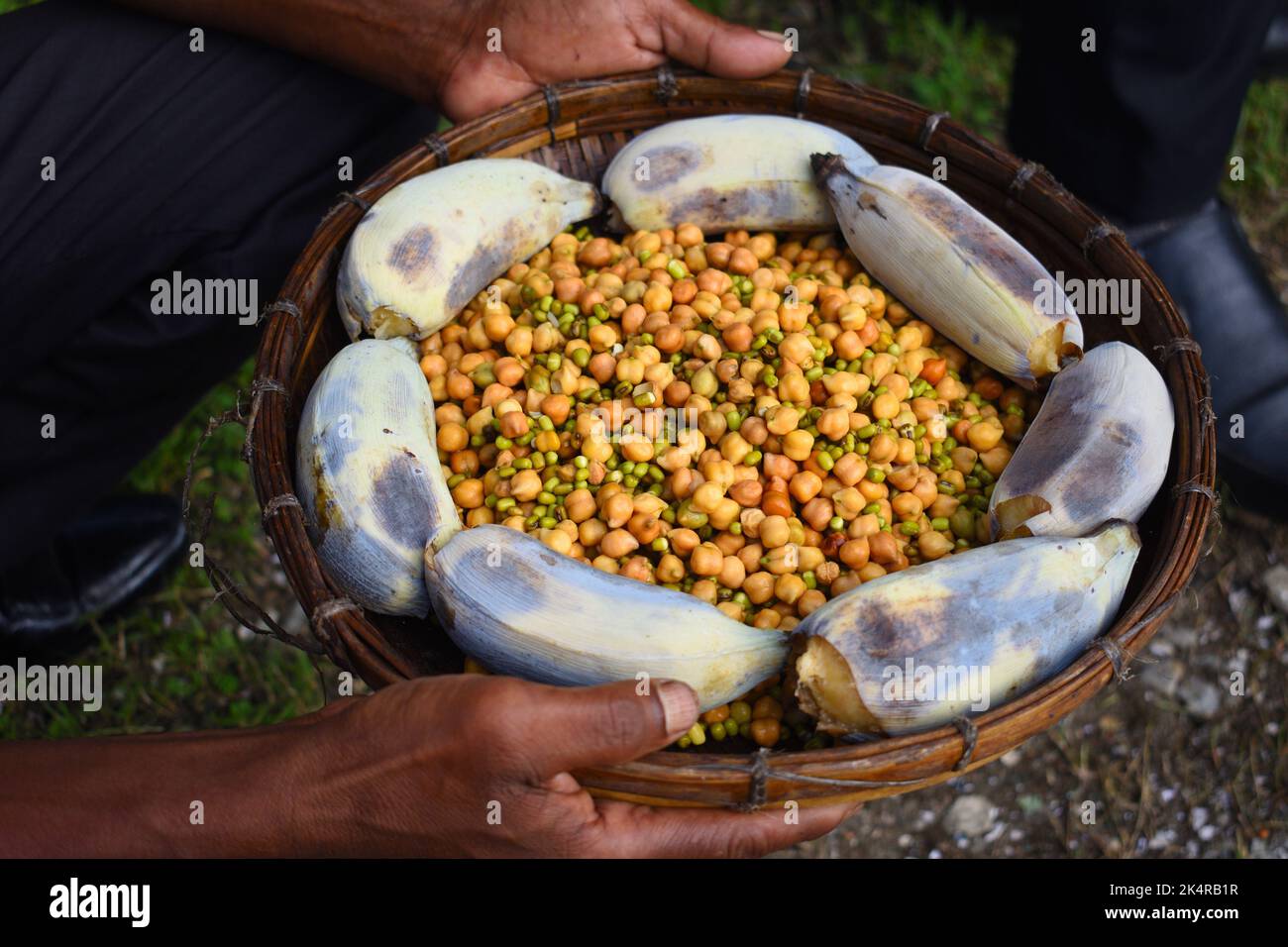 A person holding a basket  full of White chickpea (kabuli chana) and banana Stock Photo
