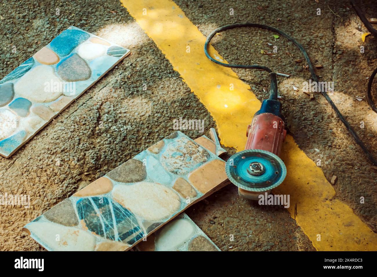 Old red angle grinder with rotary blade on aluminum surface with tiles