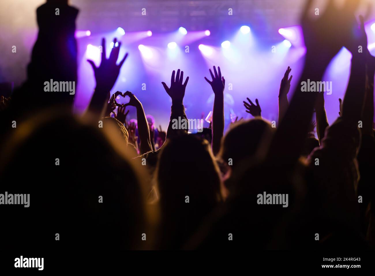 Crowd at concert - Cheering crowd in front of bright colorful stage lights Stock Photo
