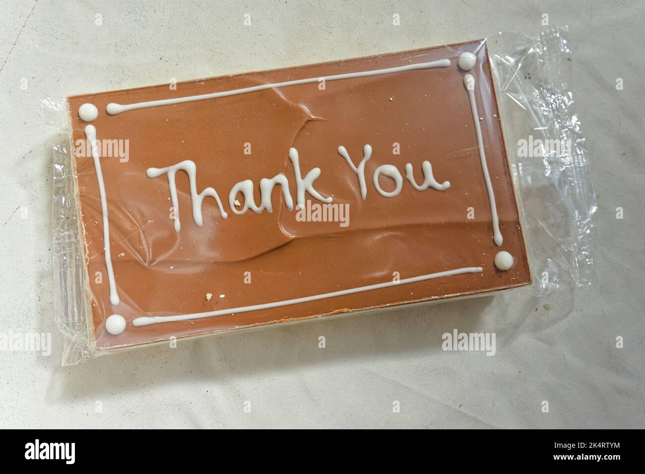 Thank You message handwritten in white on shortbread cake with toffee icing Stock Photo