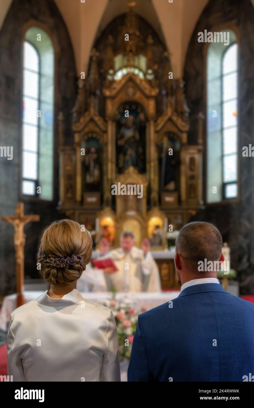 Newlyweds standing in front of the altar. Priest givin a  blessing. Stock Photo