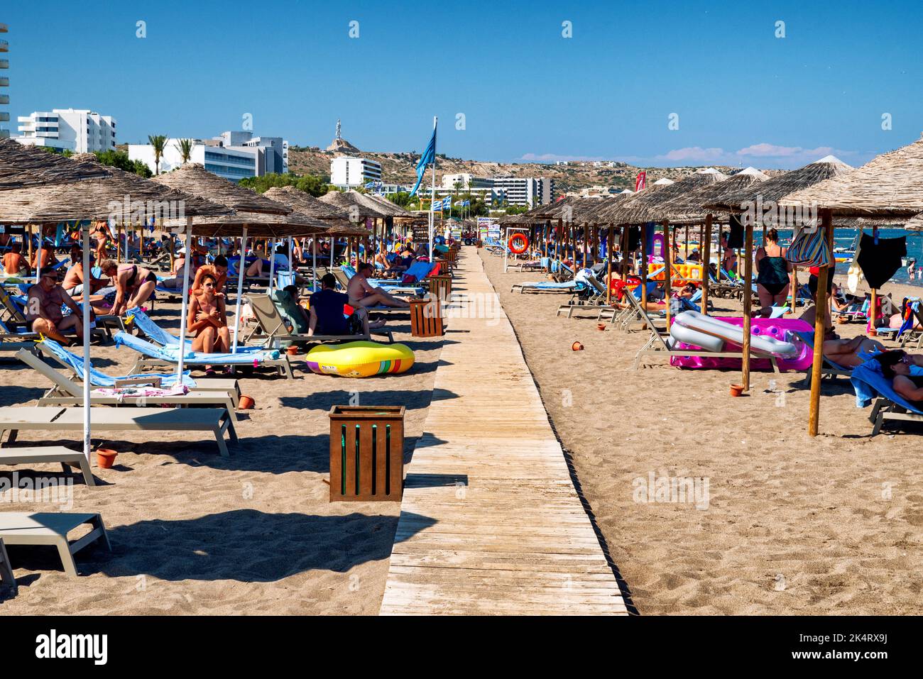 FALIRAKI, GREECE - JUN 29, 2022: People relaxing under sunshades on sandy beach at resort Faliraki in Rhodes island Stock Photo