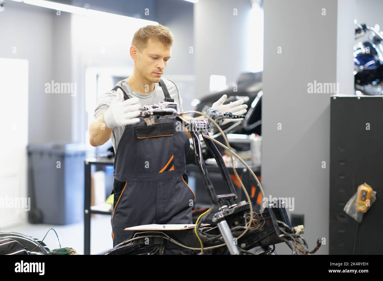 A man mechanic repairs the steering wheel of a motorcycle Stock Photo