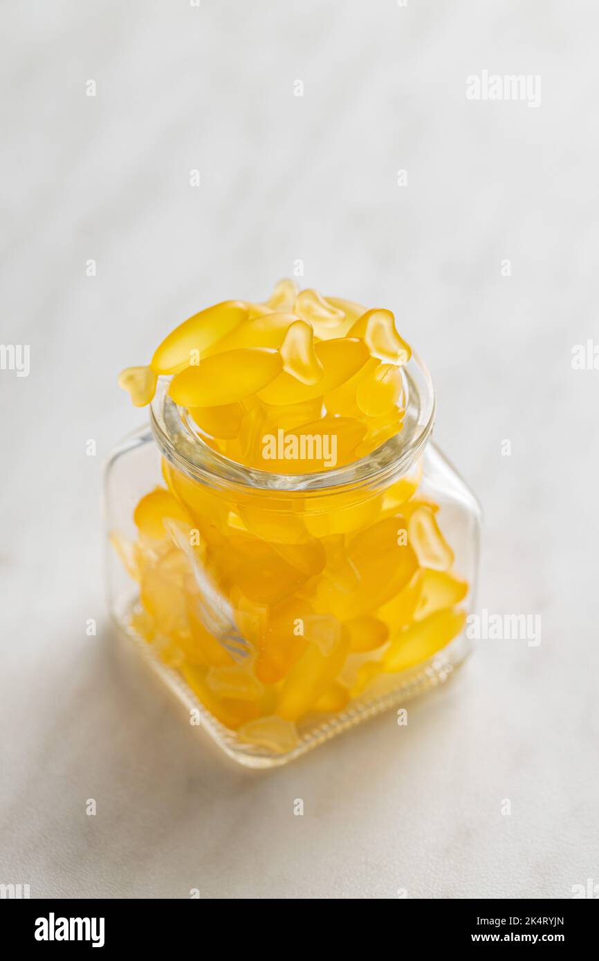 Fish oil capsules. Yellow omega 3 pills in jar on the white table. Stock Photo