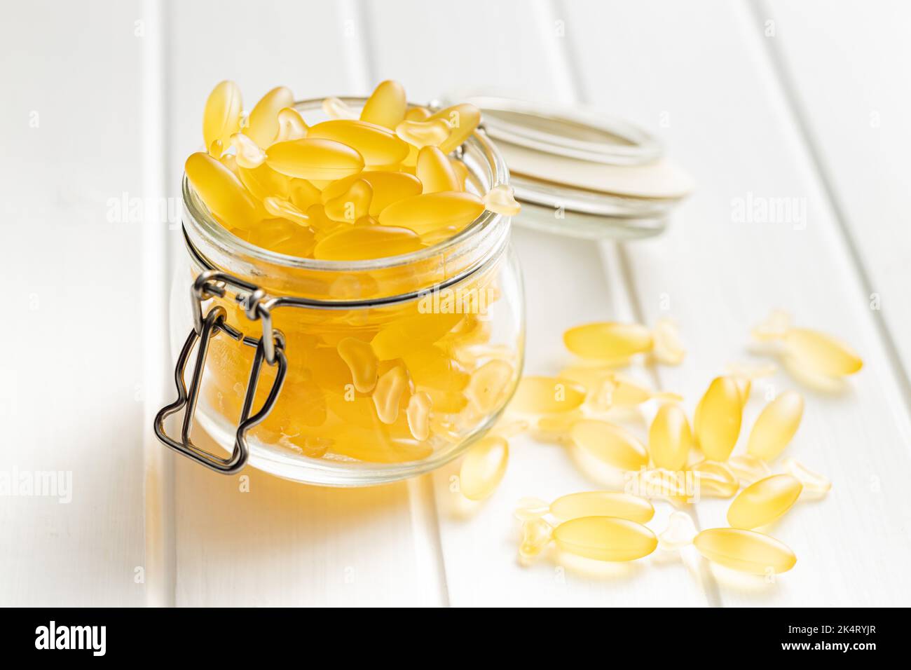 Fish oil capsules. Yellow omega 3 pills in jar on the white table. Stock Photo