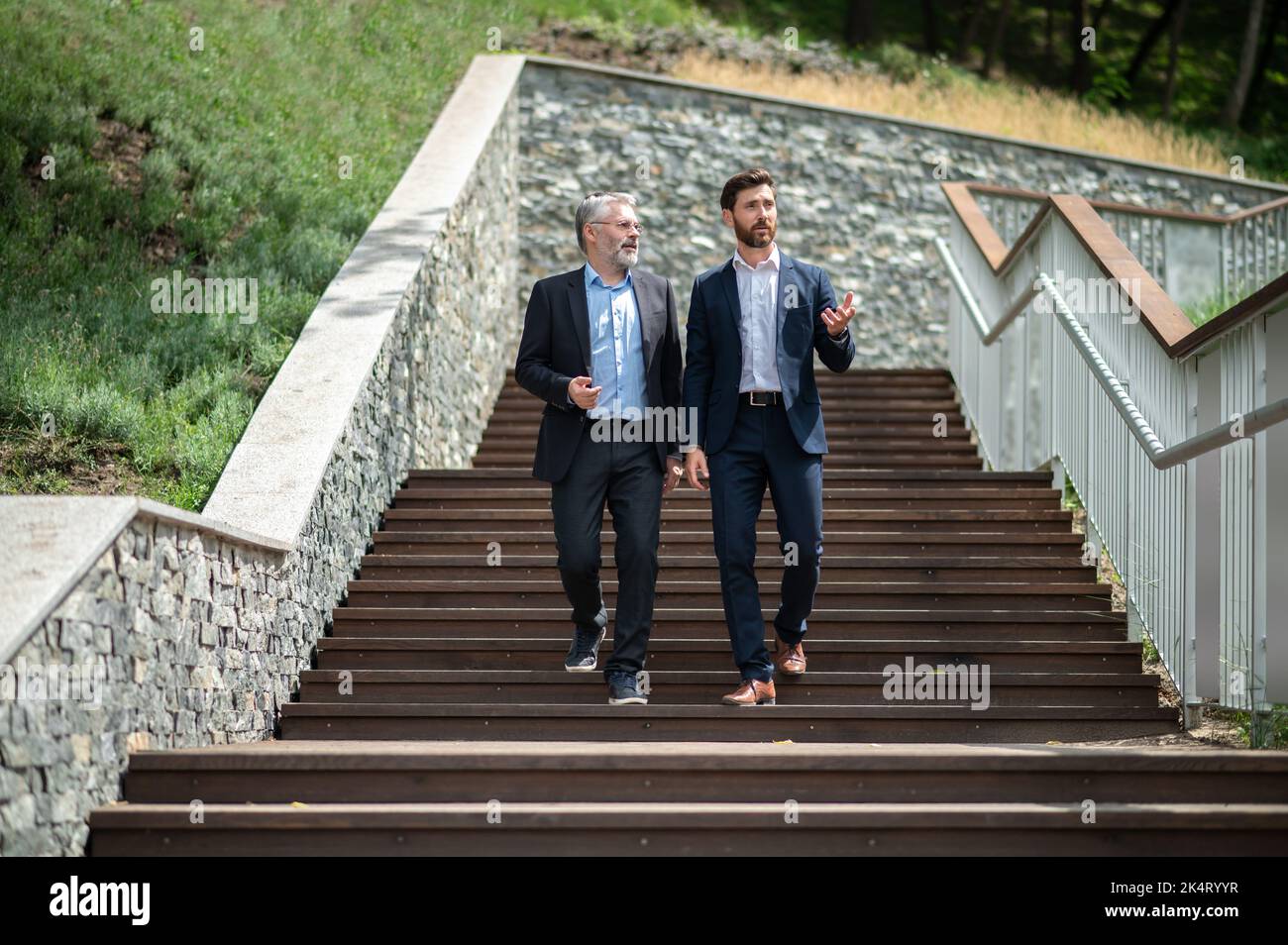 Two businessmen walking down the stairs and talking Stock Photo - Alamy