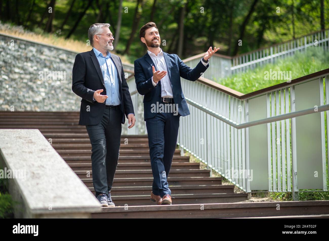 Two businessmen walking down the stairs and talking Stock Photo