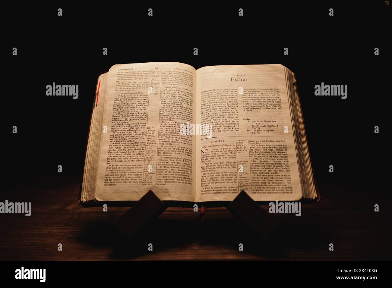 A closeup shot of a historic old Bible open on the Esther pages on display in a dark room Stock Photo
