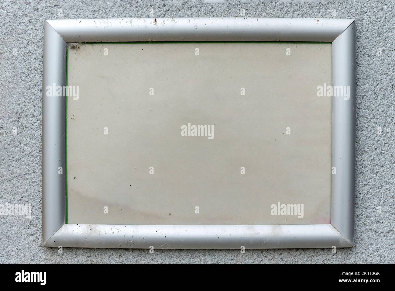 Old weathered information notice board sign on a wall with a white painted wood frame and a blank empty surface with copy space for a bulletin or mess Stock Photo