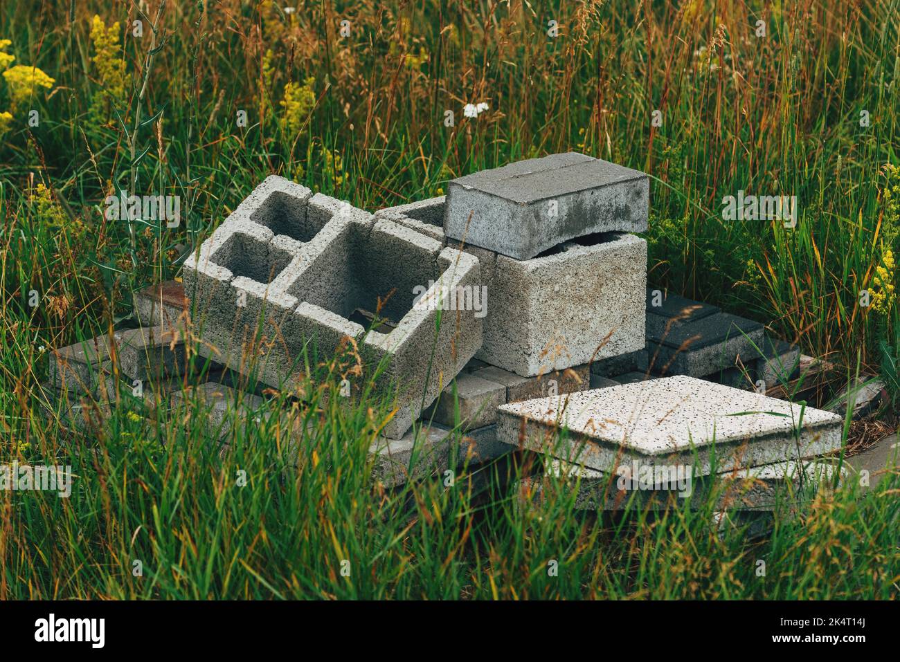 Cement blocks construction material in deep grass, selective focus Stock Photo