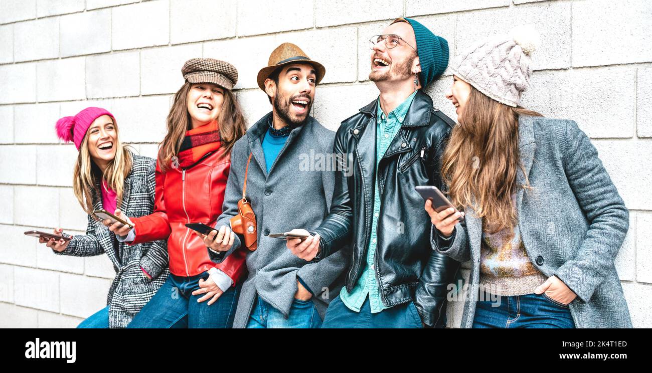 Happy friends using mobile smart phones at university wall - Young people having fun with contact tracing app - Technology addiction concept with alwa Stock Photo