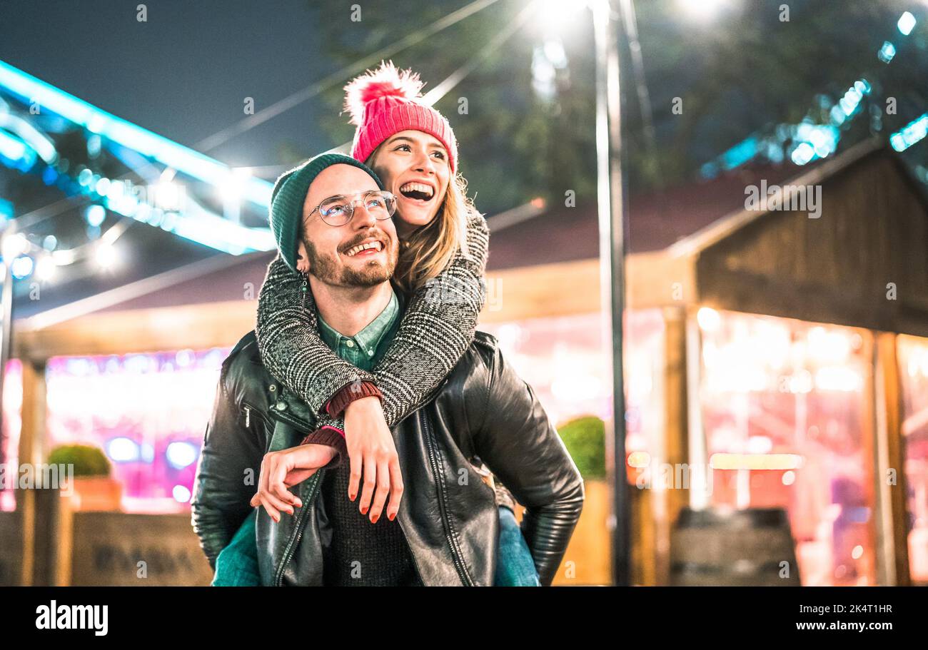 Happy couple in love enjoying winter travel time outdoor - Handsome guy with nice girl on piggy back moment - Relationship concept with boyfriend and Stock Photo