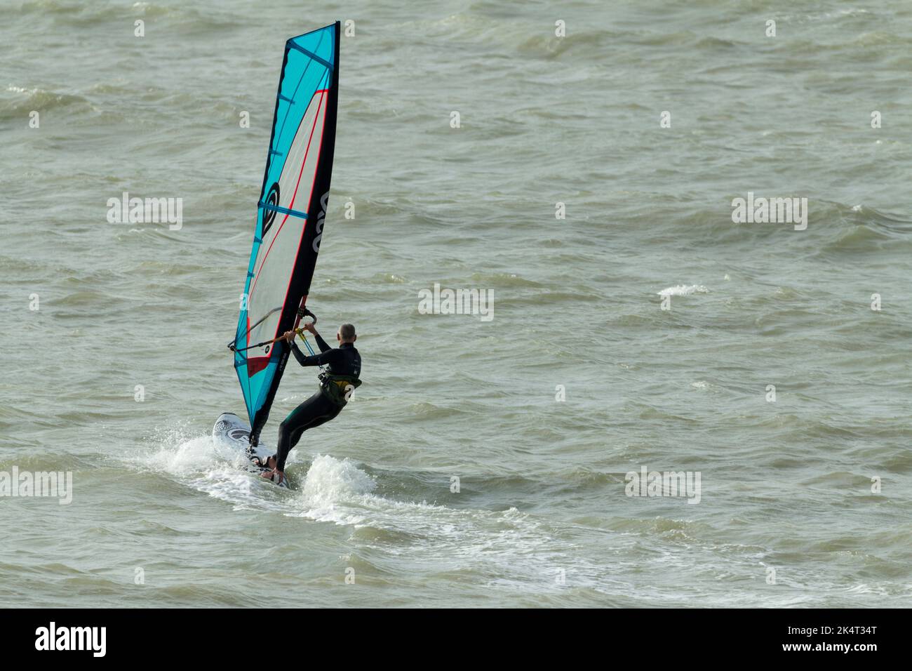 Water sport wind surfing in the sea with sail for catching the wind to propel the board and surfer sail is tilted and turned to steer and catch wind Stock Photo